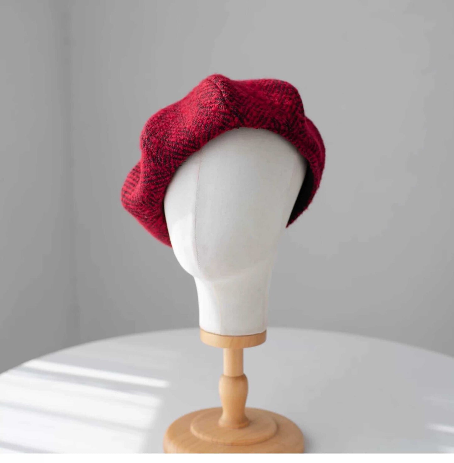 Red knitted beret on a mannequin head against a gray background