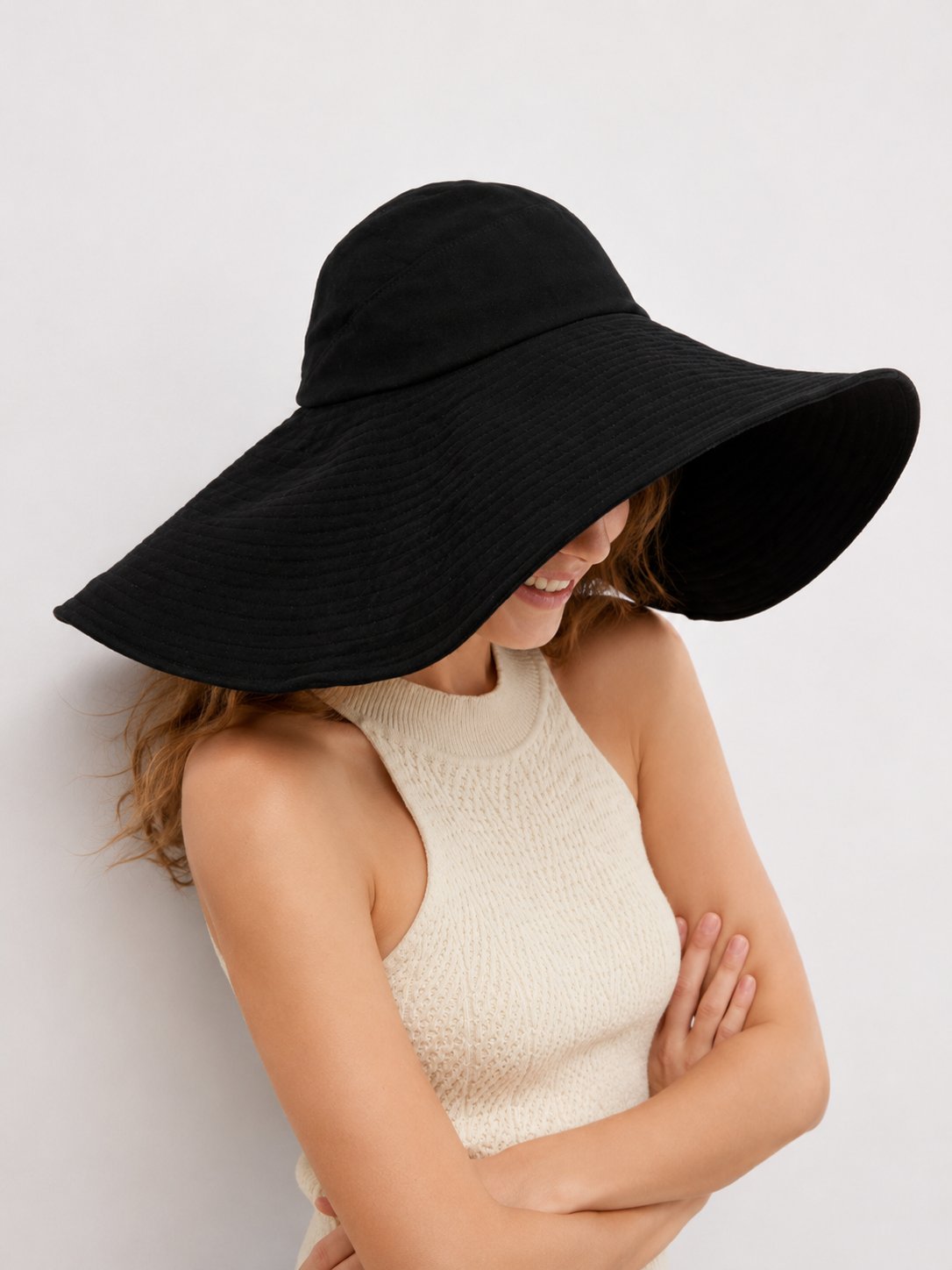 Black oversized sun hat shading face, side view
