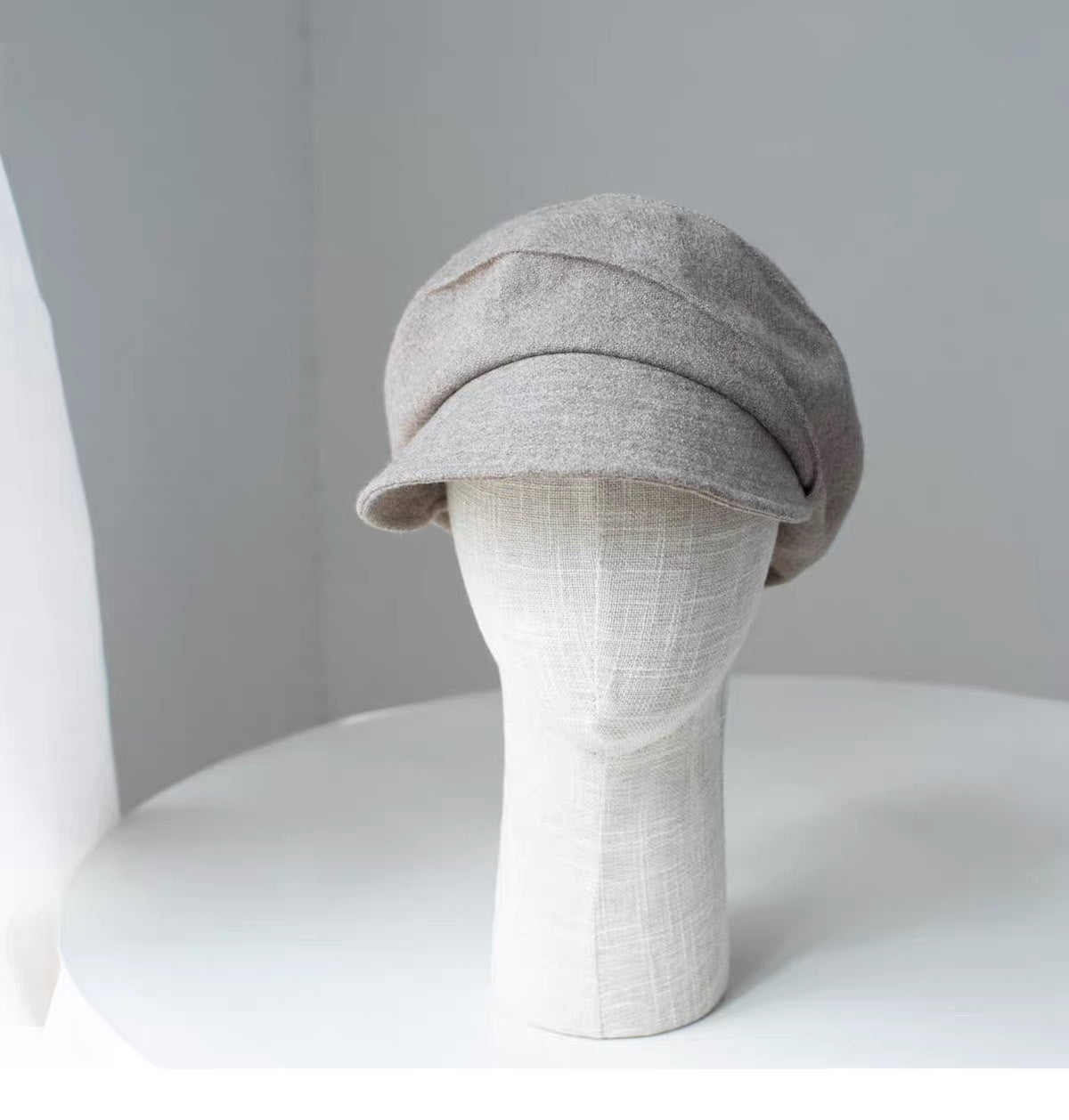 Beige 100% wool newsboy cap shown from the front on a display form