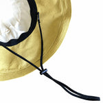 Close-up of adjustable black drawstring chin cord on yellow bucket hat
