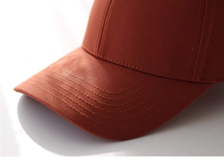 Close-up of tonal stitching on the curved rust-orange baseball cap brim