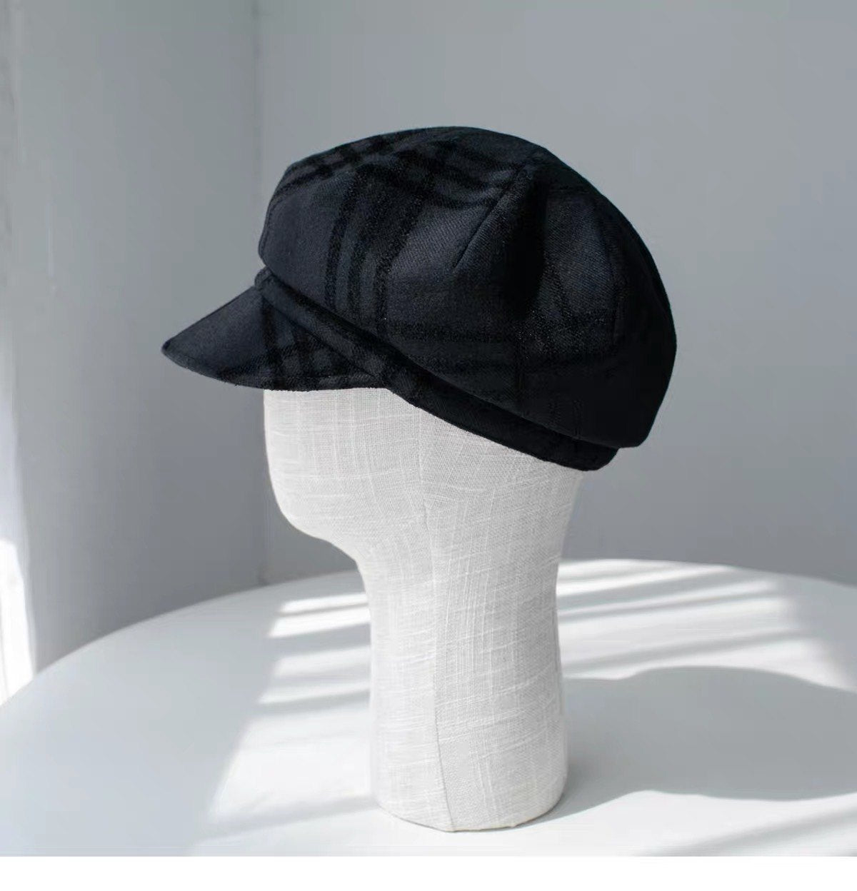 Black fine woven wool newsboy cap shown from the left side