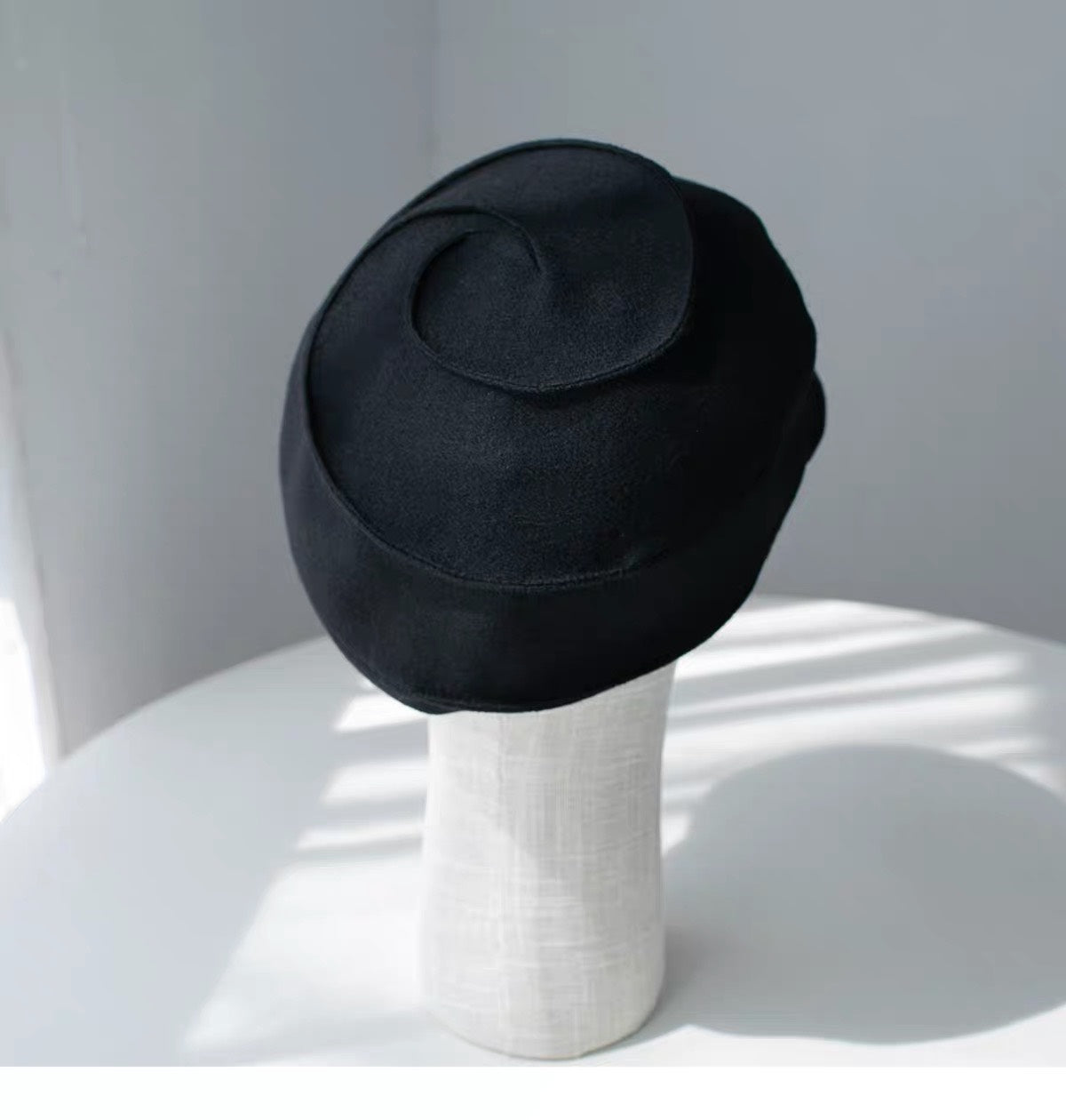 Rear and top view of the black wool newsboy cap's curved panel construction