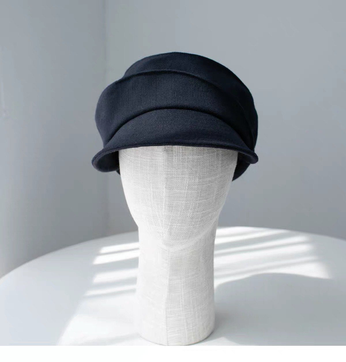 Navy 100% wool newsboy cap shown from the front on a display form
