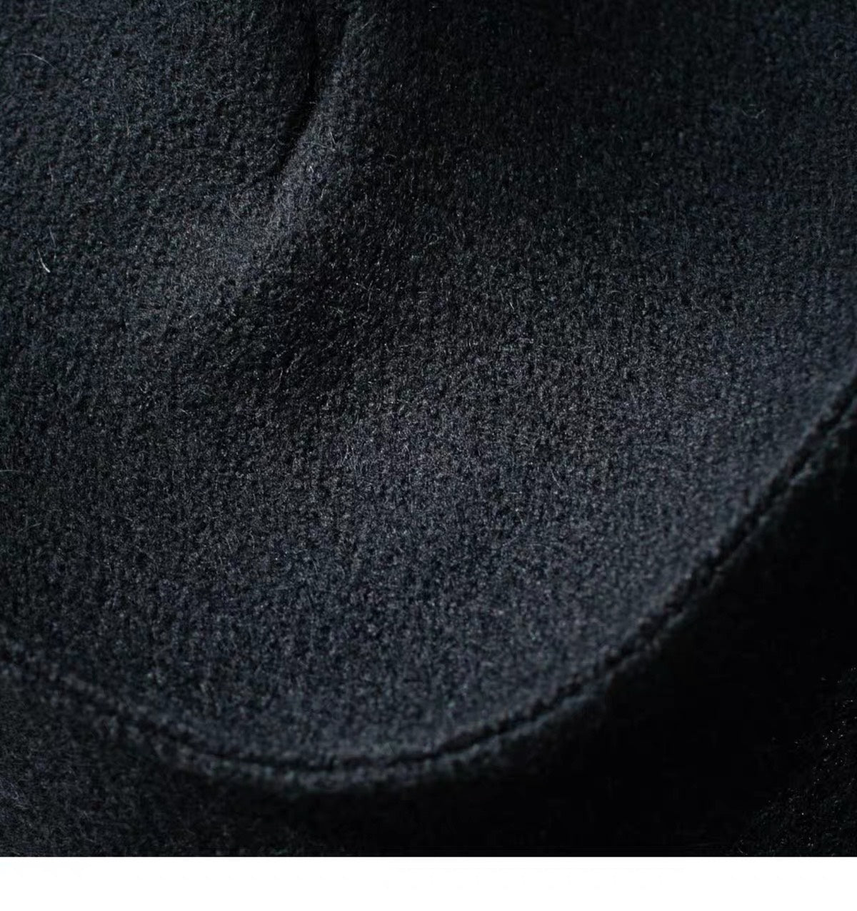 Close view of the black 100% wool surface and curved seam