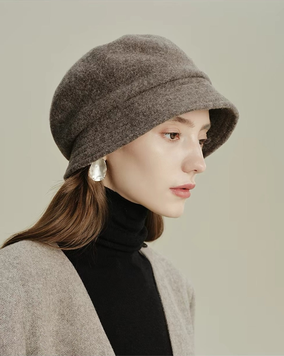 Close-up side view of a taupe wool cloche hat on a female model