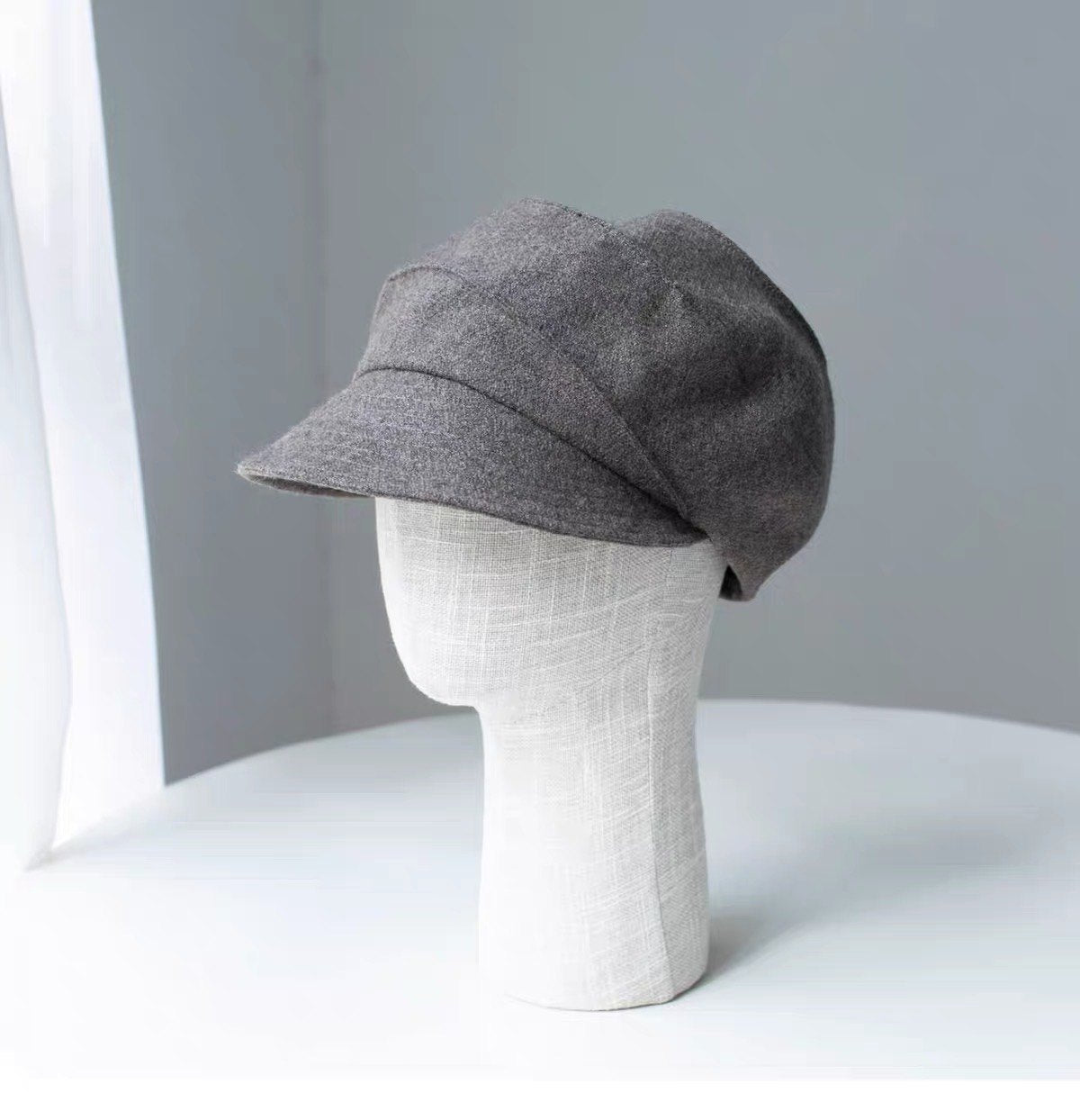 Khaki 100% wool newsboy cap shown from the front on a display form