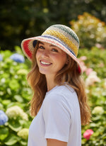 Woman wearing colourful rainbow straw hat - three quarter view outdoors