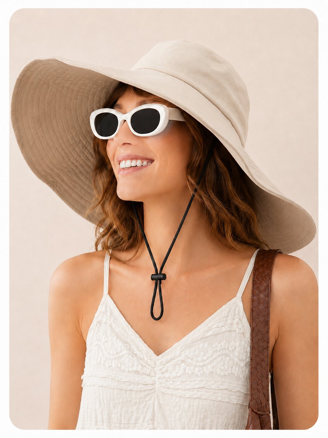 Smiling woman in beige wide-brim cotton sun hat with white sunglasses and tote bag