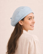 Woman wearing light blue cotton linen French beret