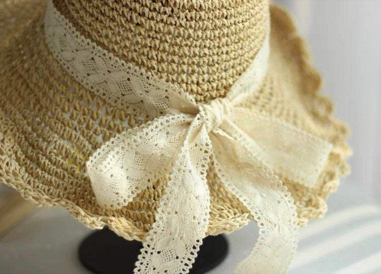 Close-up detail of scalloped straw hat brim and lace bow decoration