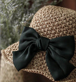Close-up detail of satin bow on camel straw hat