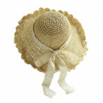 Beige scalloped straw hat with lace bow, top-front view on white background