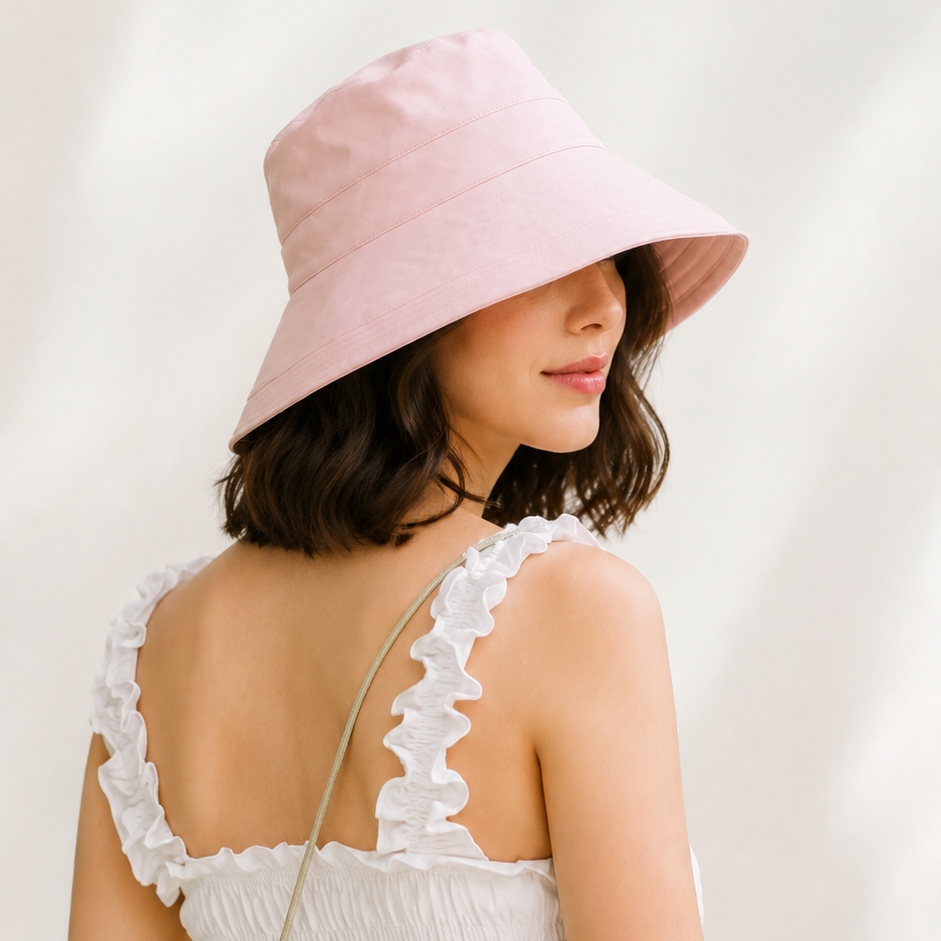 Woman wearing a pink bucket hat and white dress against a light background