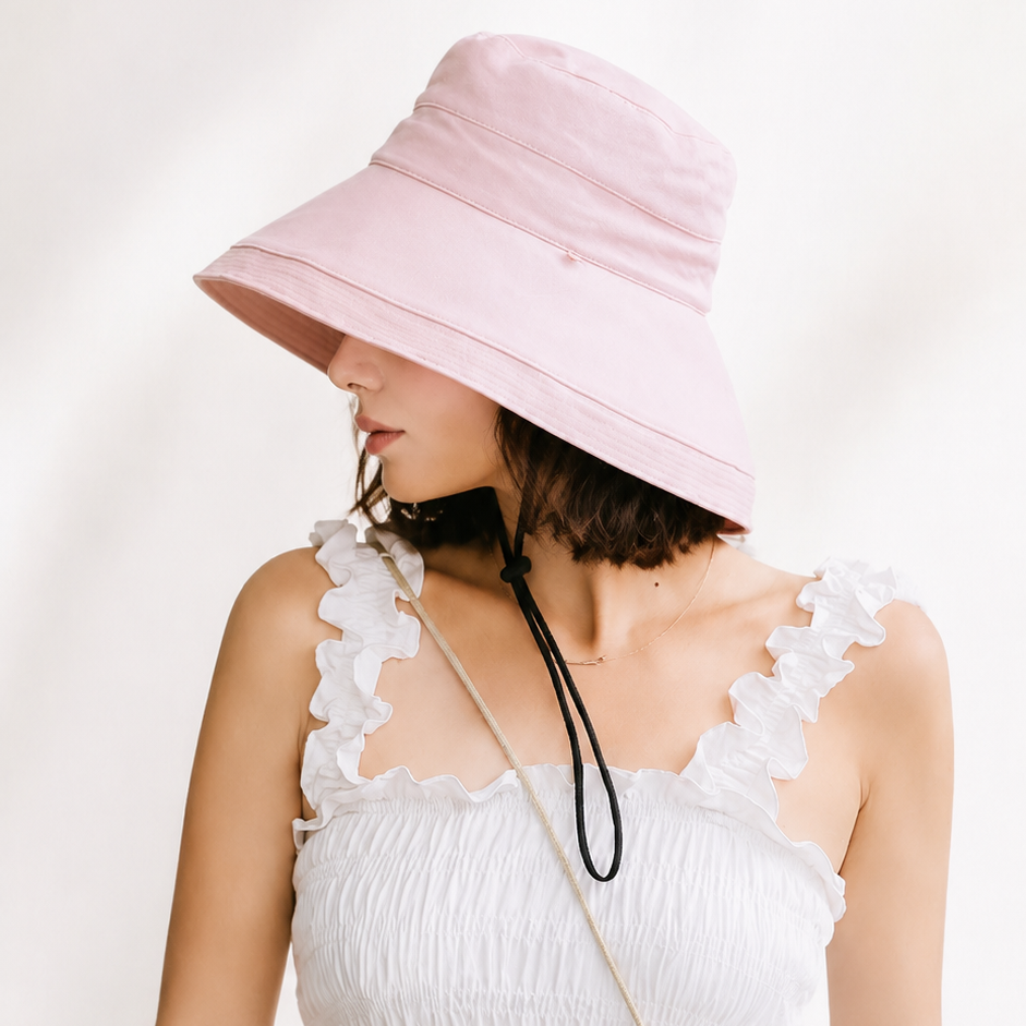 Woman wearing a pink bucket hat and white dress against a white background