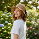 Woman wearing straw bucket hat with bow, back view, outdoor garden