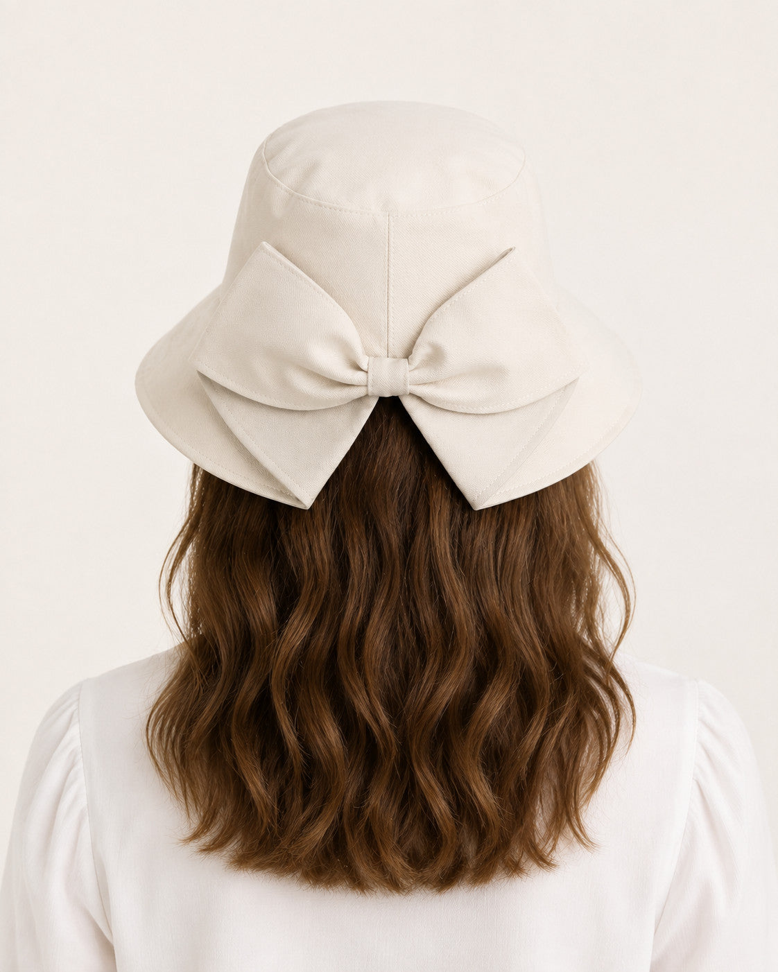 Rear view of woman wearing beige bucket sun hat with oversized bow