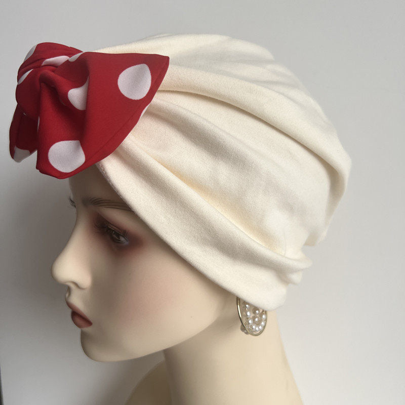 Beige modal cotton turban hair wrap with red polka dot bow on mannequin