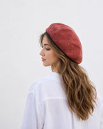 Woman wearing chestnut red linen French beret, back view