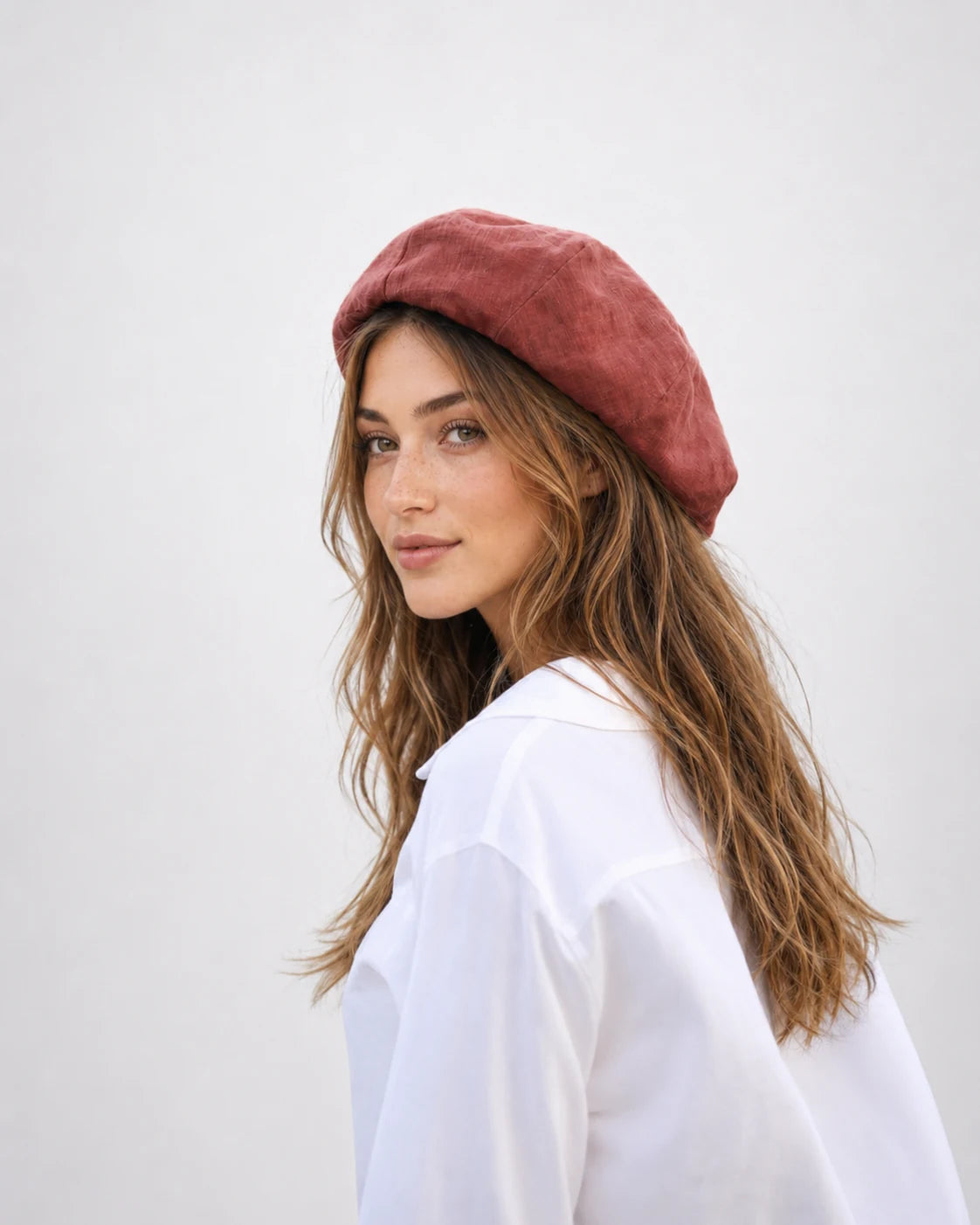 Woman wearing chestnut red linen French beret, side view