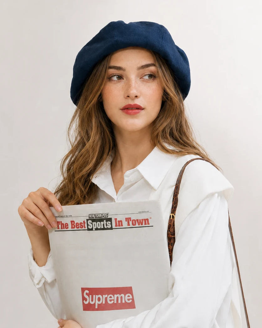 Woman in navy linen French beret holding a newspaper