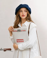 Woman in navy linen French beret holding a newspaper