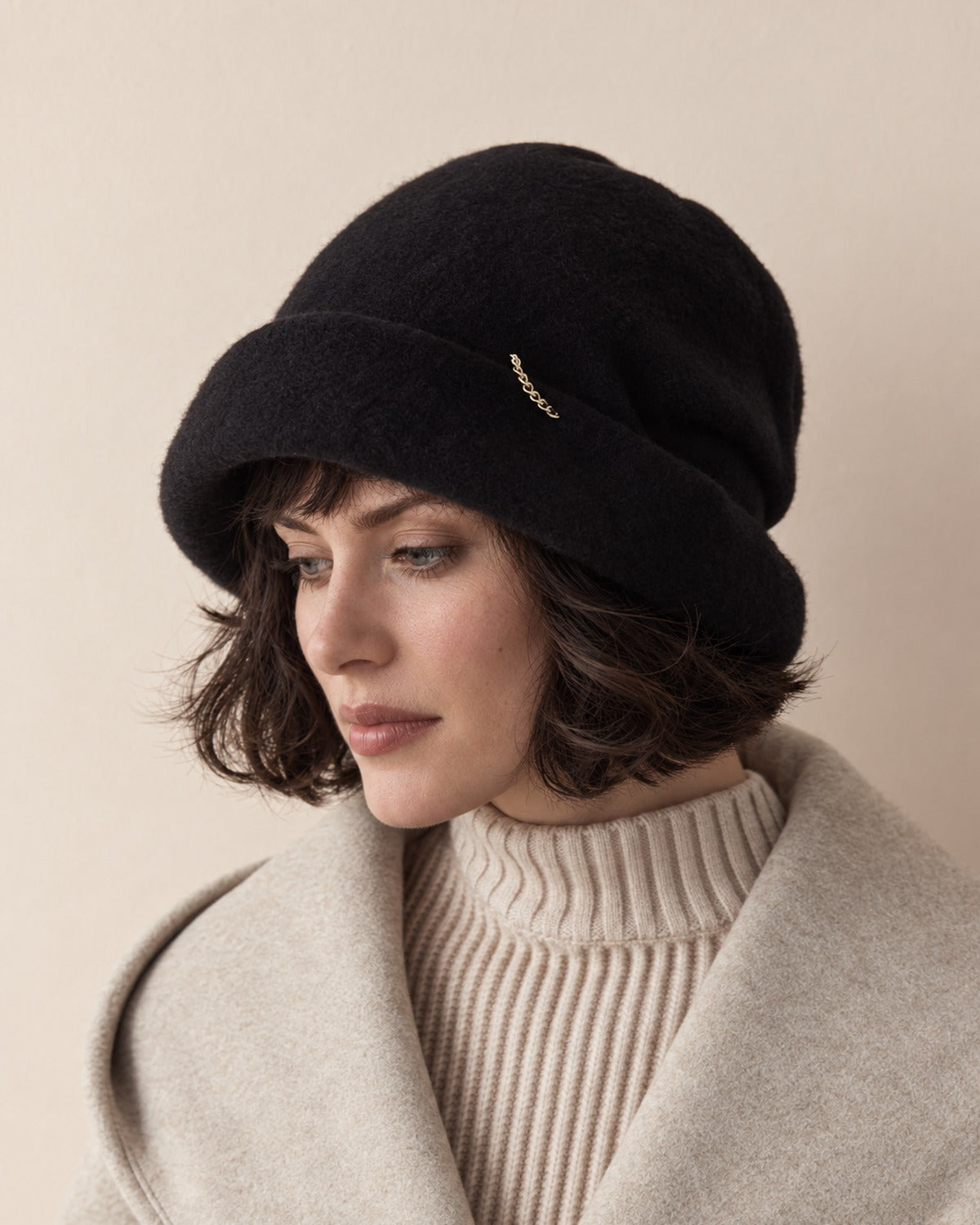 White female model wearing the Classic Black wool slouchy beret in a quiet three-quarter studio view