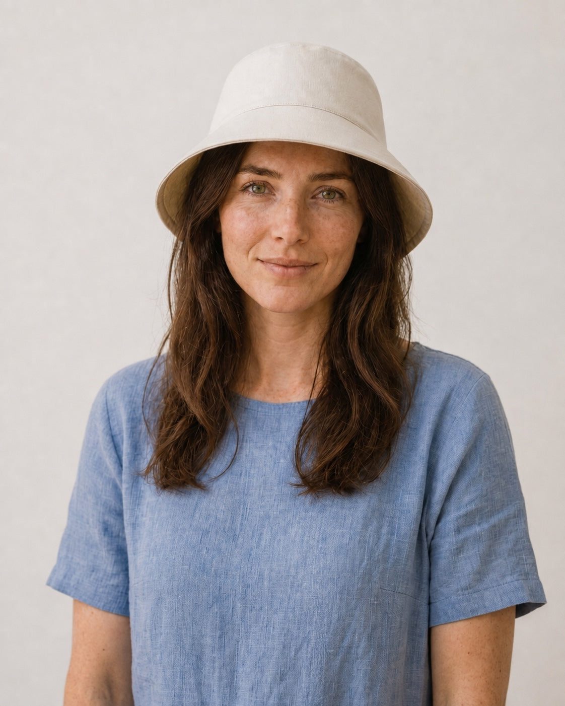 Front view of woman wearing beige bucket sun hat with oversized back bow
