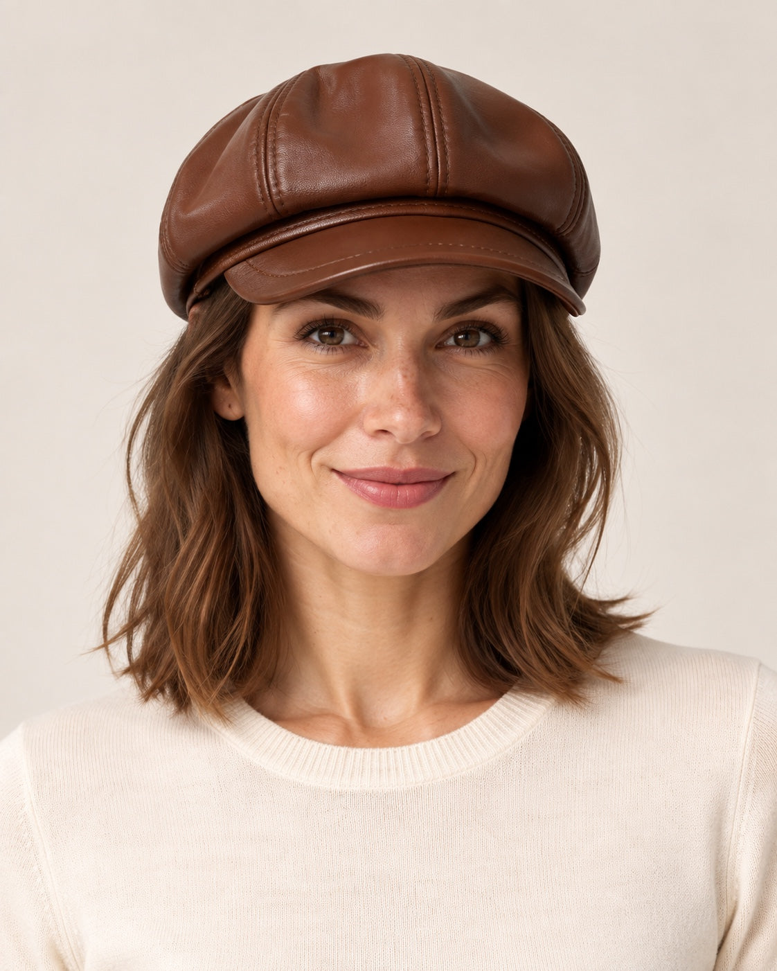 Woman in an ivory knit top wearing the brown genuine leather short-brim newsboy cap, front view