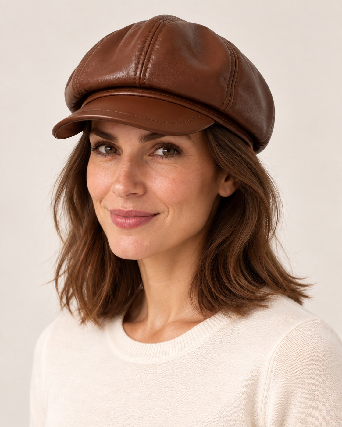 Woman in an ivory knit top wearing the brown genuine leather short-brim newsboy cap, three-quarter view