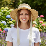 Woman wearing scalloped straw sun hat with lace bow in garden - front view