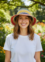 Woman wearing rainbow stripe straw bucket hat - front view in garden