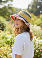 Woman wearing rainbow straw hat - back view showing hat back in garden