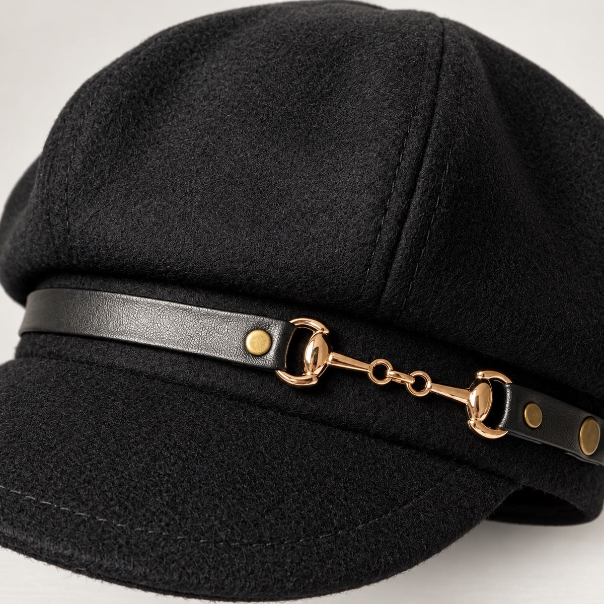 Black newsboy cap close-up showing gold-tone chain and black band