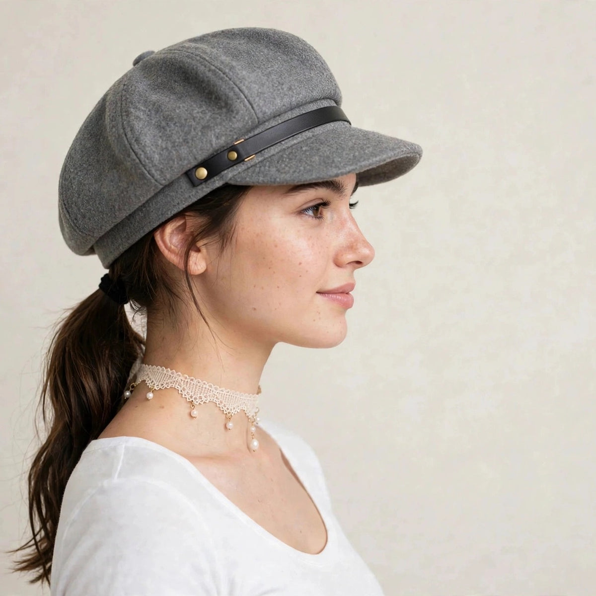Gray wool blend newsboy cap with gold-tone chain, worn by model, side view