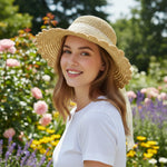 Woman wearing scalloped straw sun hat with lace bow in garden - three quarter view