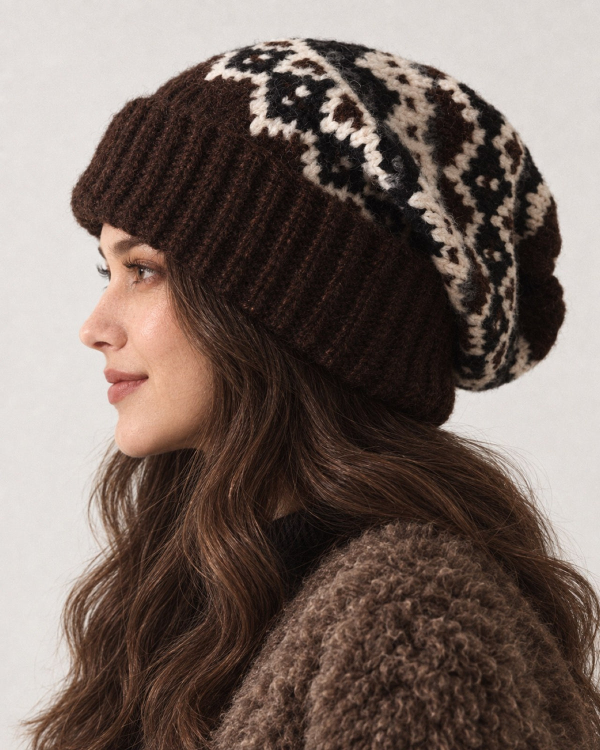 Young woman wearing the Coffee Fair Isle oversized slouchy beanie, profile studio portrait