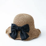 Women's camel straw bucket hat with black bow, white background
