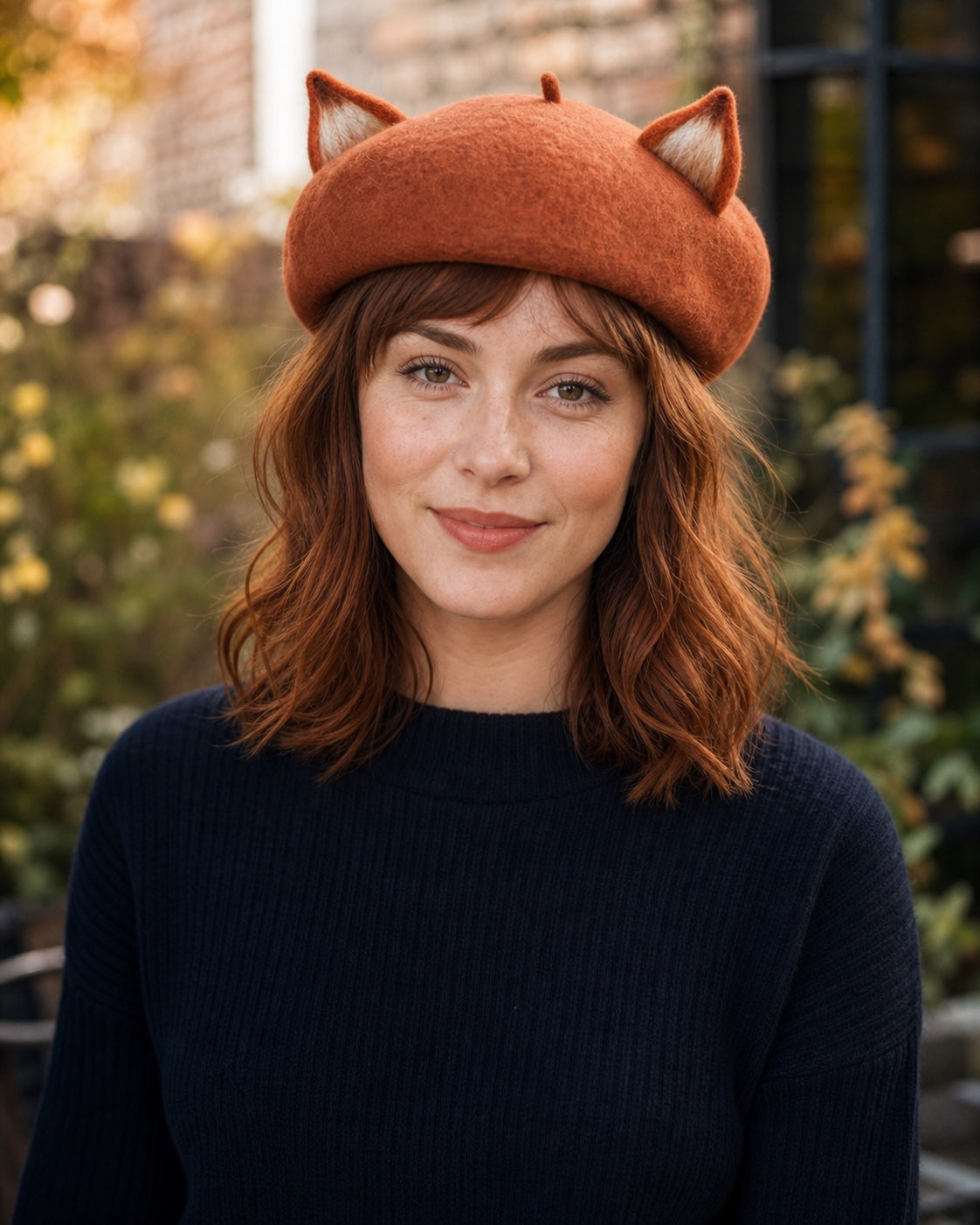 White model wearing the rust-brown wool fox-ear French beret in an autumn garden