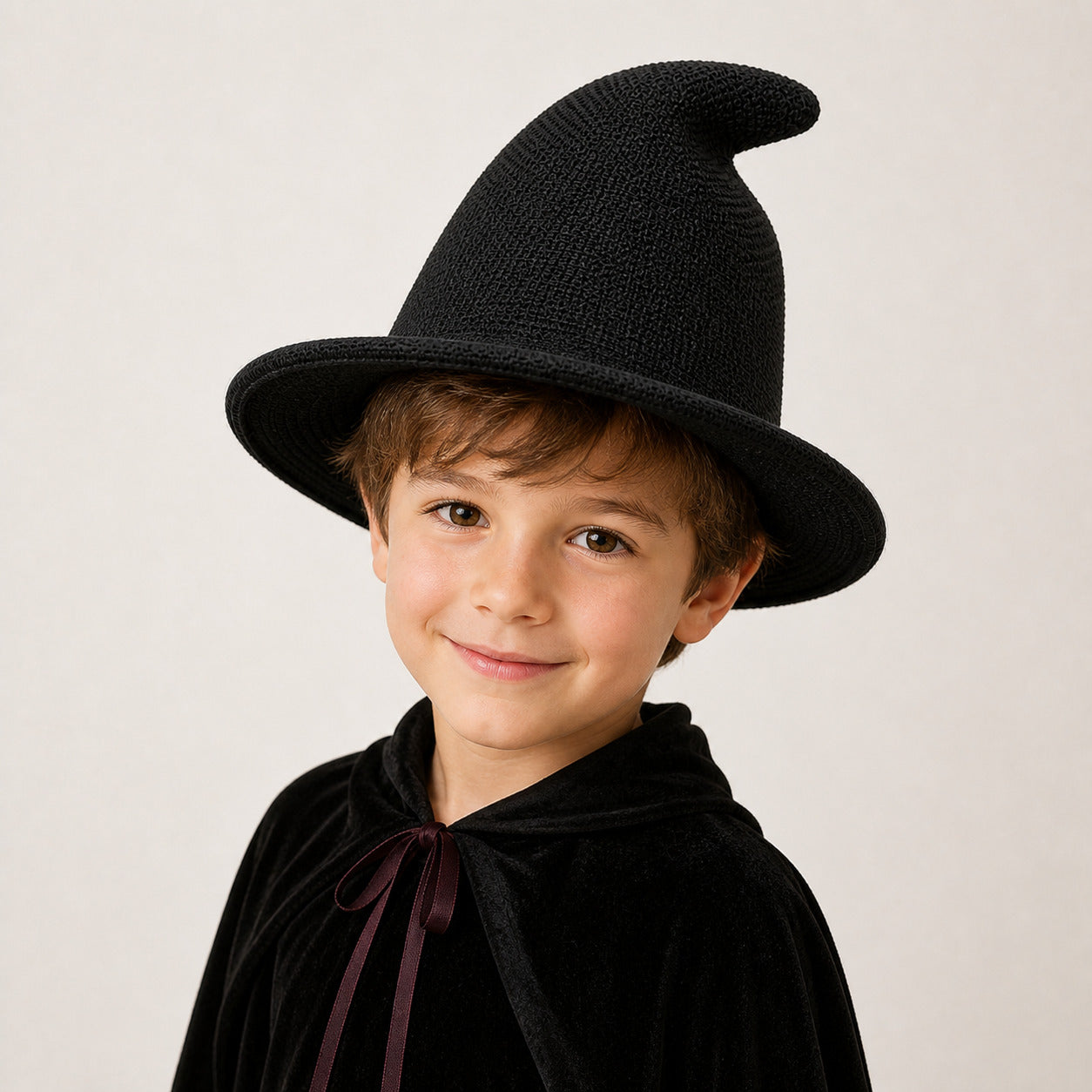 Boy wearing a black knitted witch hat and Halloween wizard costume