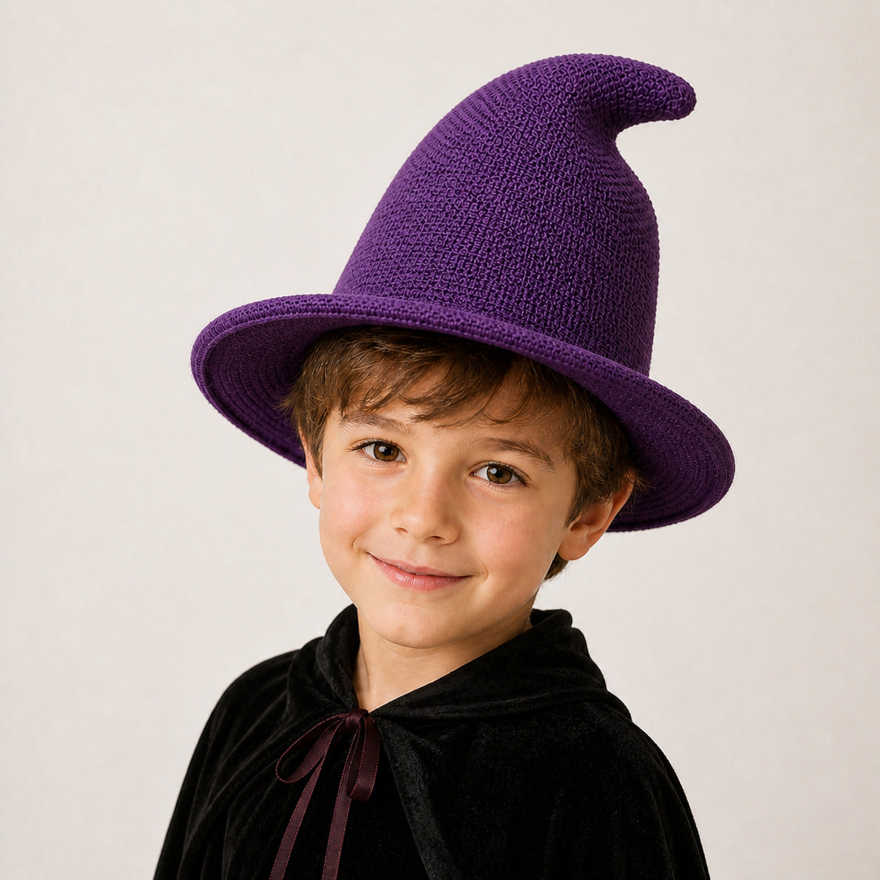 Boy wearing a deep purple knitted witch hat and Halloween wizard costume