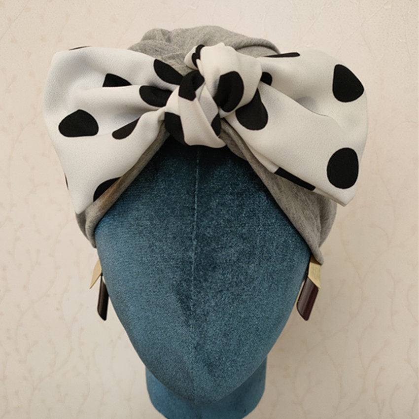 Light grey polka dot bow turban hair wrap displayed on a mannequin
