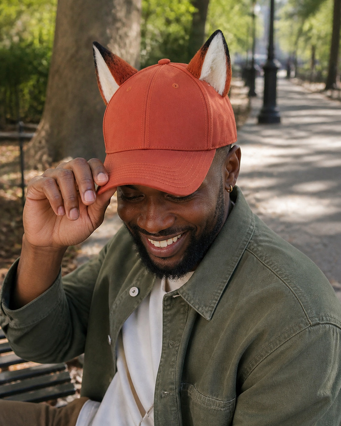 Adult model gently adjusting the curved brim of the rust-orange hand-sewn fox-ear baseball cap