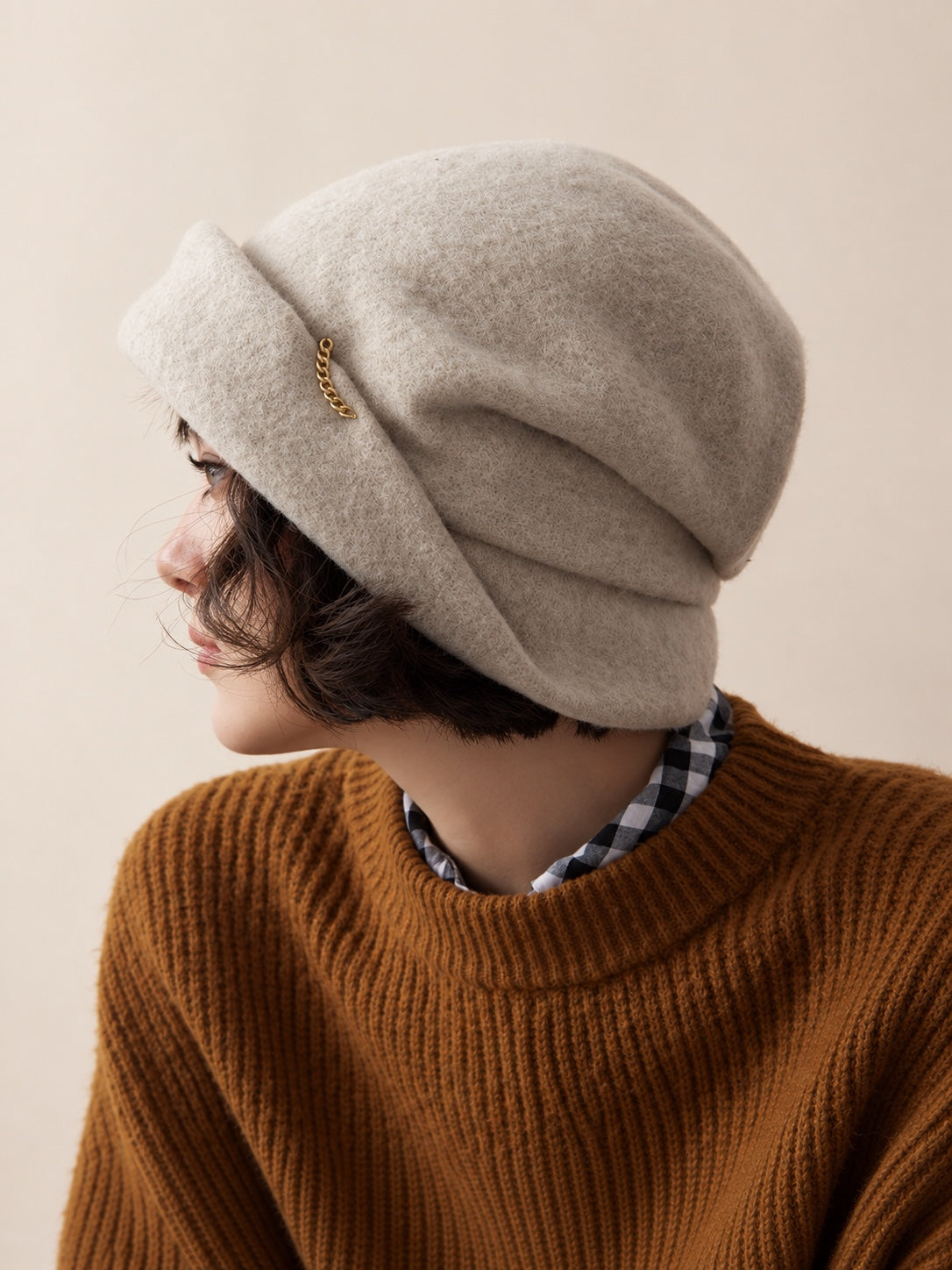White female model wearing the Oat Almond wool slouchy beret, rear three-quarter studio view