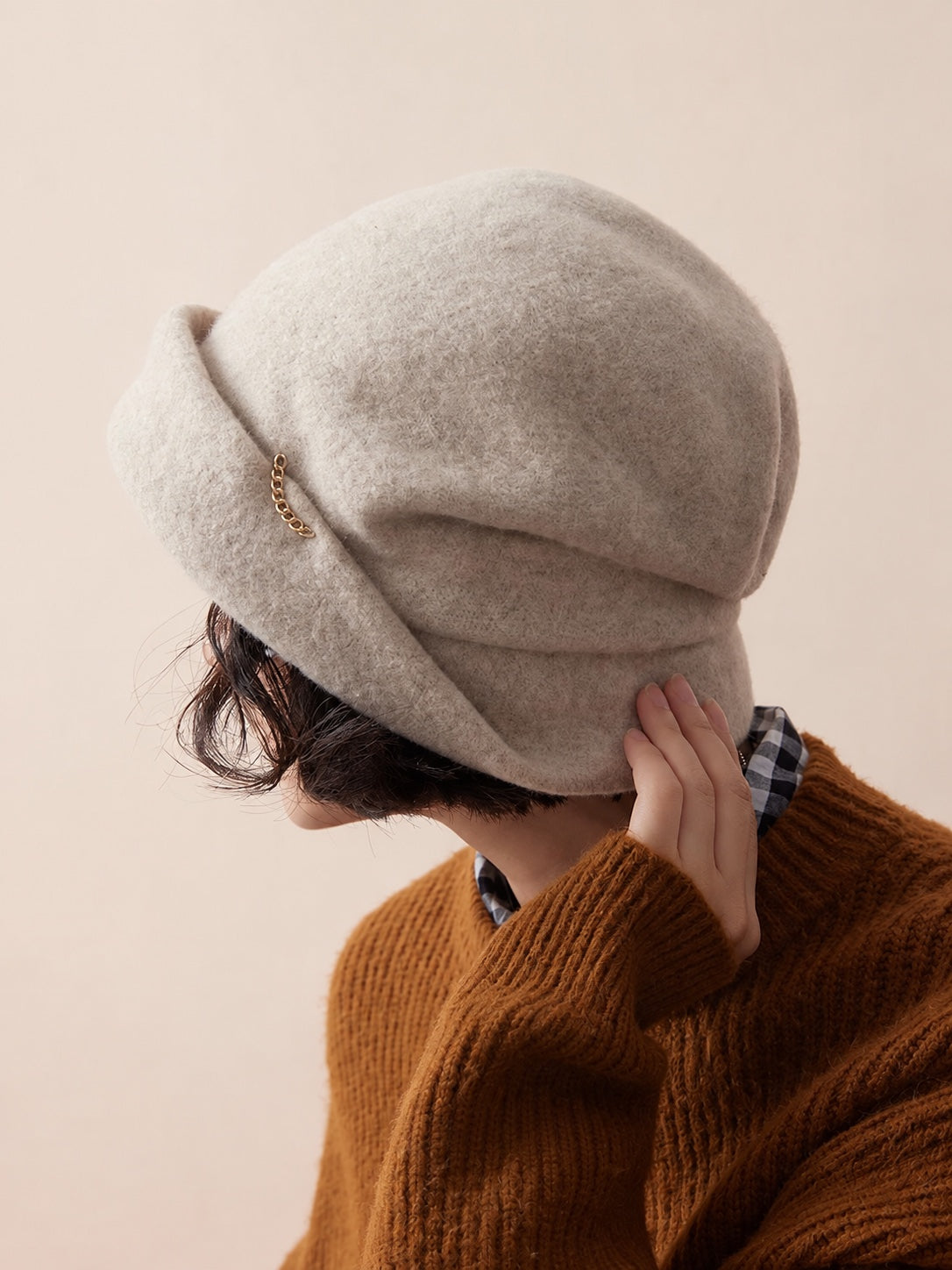 Woman wearing the Oat Almond wool slouchy beret with short brim and gold chain detail