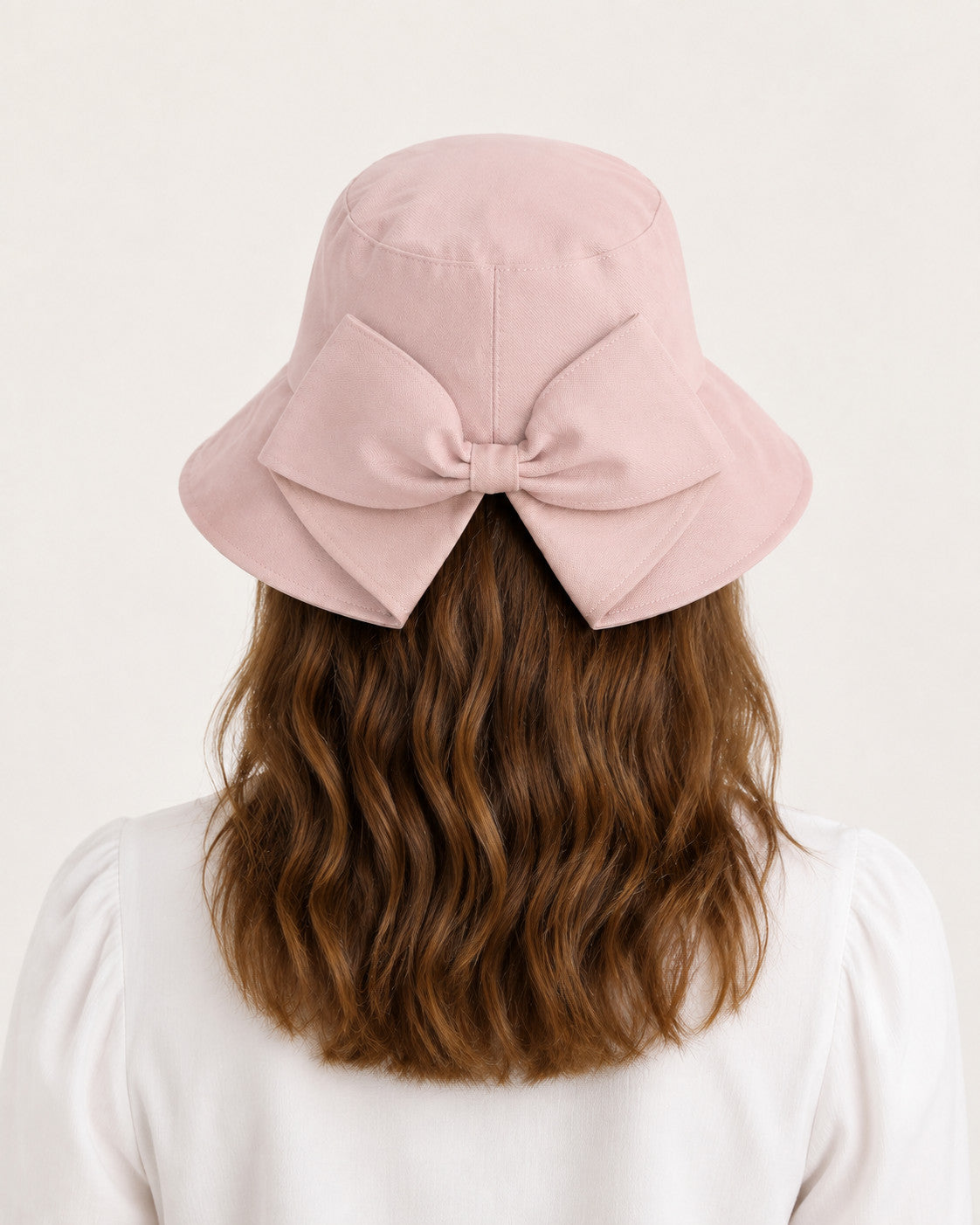Rear view of woman wearing pink bucket sun hat with oversized bow