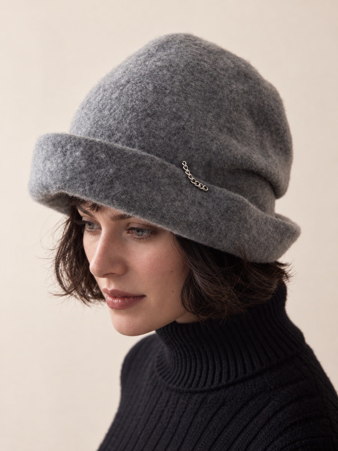 White female model wearing the Smoke Grey wool slouchy beret in a downward three-quarter studio view