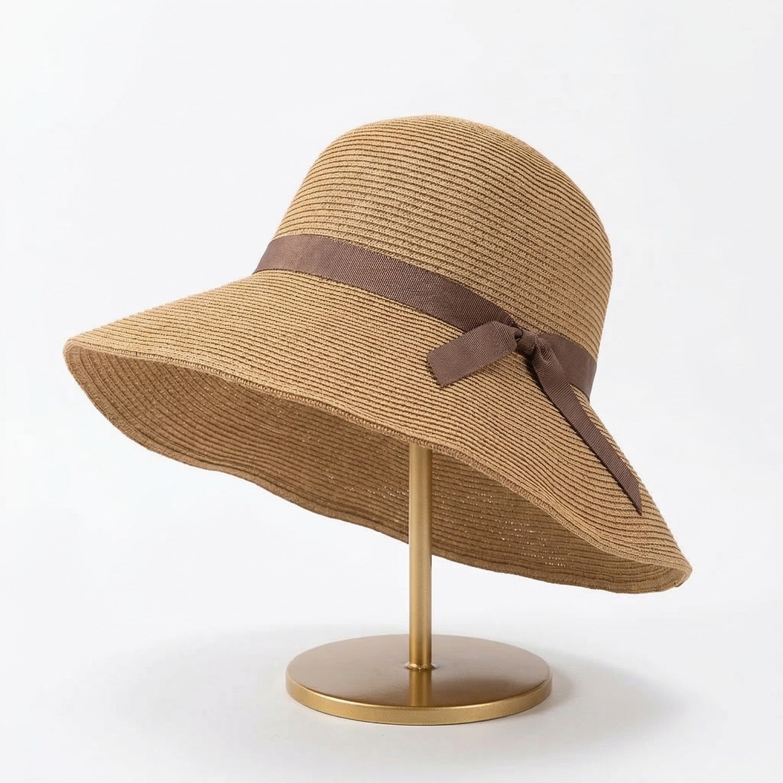 Foldable straw cloche hat with brown ribbon bow on display stand