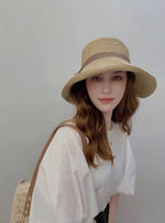 Woman wearing straw cloche sun hat with brown ribbon bow