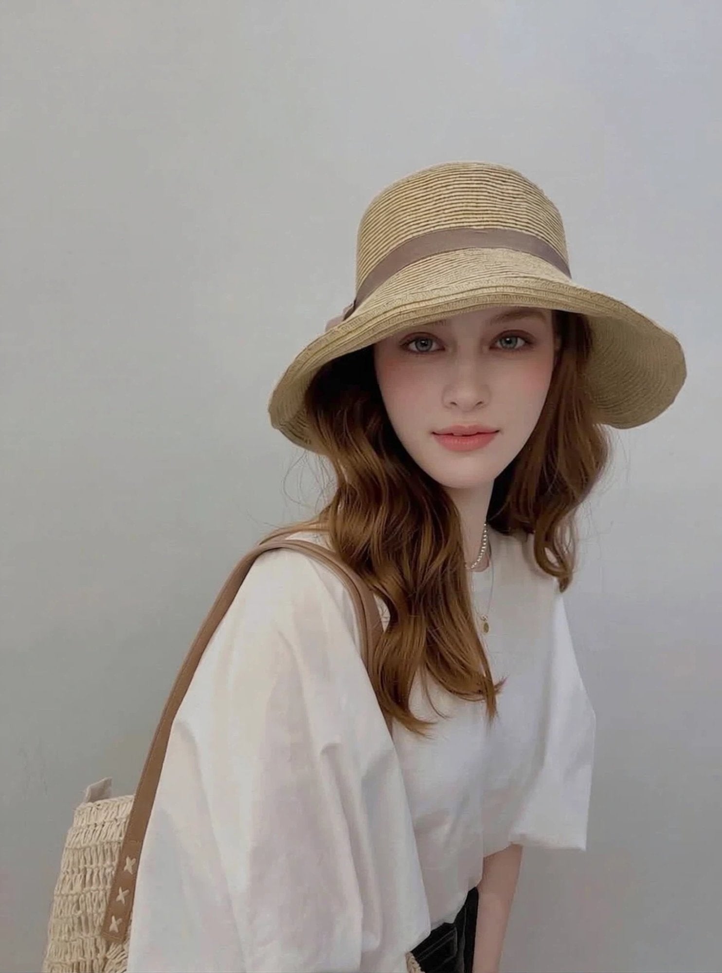 Woman wearing straw cloche sun hat with brown ribbon bow